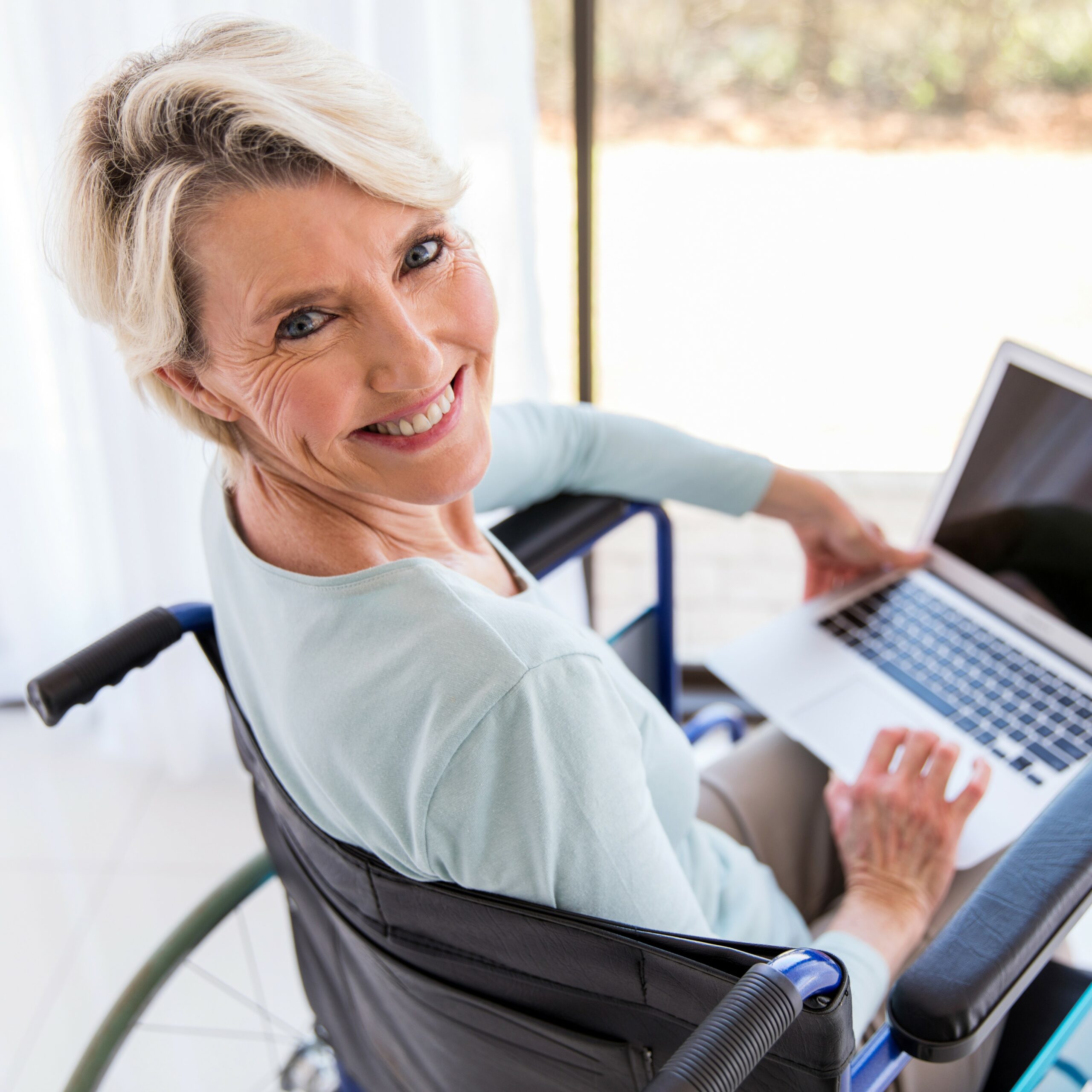 pretty disabled middle aged woman with laptop computer at home